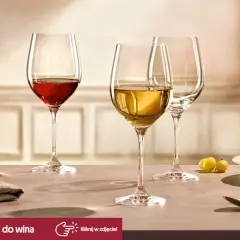 Eleganckie kieliszki do wina, jeden z czerwonym winem, drugi z białym, gotowe na degustacje. Obok winogrona i sztućce.
