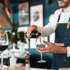 Doświadczony sommelier wina nalewa czerwone wino do kieliszka w eleganckiej restauracji.