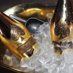 Dwie złote butelki szampana Armand de Brignac w wiaderku z lodem. To szampan drogi, symbol luksusu i celebracji.