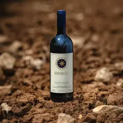 Butelka Sassicaia, uznawanego za najdroższe wino świata, stoi na żyznej ziemi, gotowa do zbiorów.