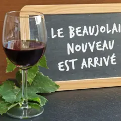 Kieliszek czerwonego wina i tablica z napisem "Le Beaujolais Nouveau est arrivé!" – to znak, że nadszedł czas na święto młodego wina.