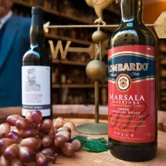 Słodkie wino deserowe Marsala Lombardo, obok kiść winogron.