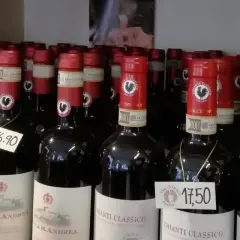 Rzędy butelek wina z kogutem na etykiecie. Na niektórych widnieją ceny: 16,90 i 17,50.