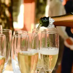 Nalewanie złotego **brut wino** do kieliszków. Bąbelki unoszą się, zapowiadając celebrację.