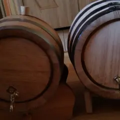 Dwa drewniane beczki, jedna z korkiem, druga z kranikiem, czekają aż coś w nich dojrzewa w dębowych beczkach.