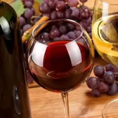 Butelka i kieliszki z winem, winogrona. Warto pamiętać o potencjalnych białym winie właściwości lecznicze.