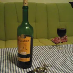 Butelka Kadarka na stole, obok kieliszek z winem. Zastanawiam się, kadarka ile procent ma w sobie?