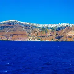 Widok na białe miasteczko na klifie nad błękitnym morzem na Santorini.