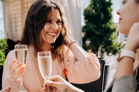 Uśmiechnięte kobiety świętują międzynarodowy dzień prosecco, wznosząc kieliszki musującego wina na tarasie.