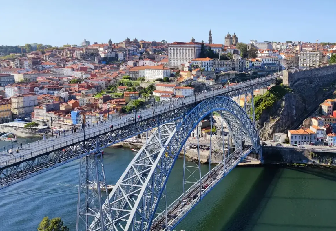 Most Louisa Martinez wino, widok na most Ponte de Dom Luís I w Porto, Portugalia, z zabytkową zabudową w tle.