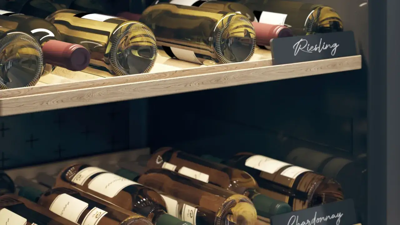 Butelki wina, w tym Riesling i Chardonnay, stoją w lodówce. Zastanawiasz się, jak długo może stać otwarte wino w lodówce?