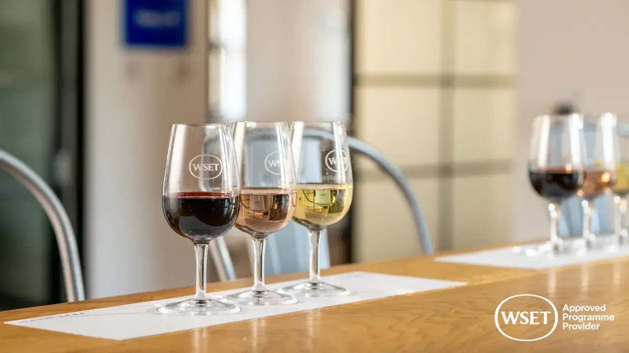 Degustacja wina w klubie: kieliszki z czerwonym, różowym i białym winem, z logo WSET.